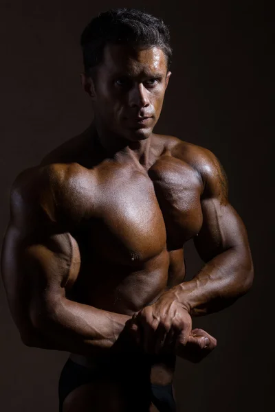 暗い背景に対して裸の胴体を持つ若いスポーツ男 — ストック写真