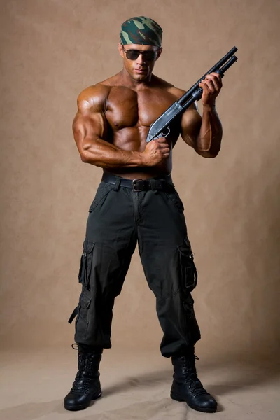 A muscular man with a gun in full view. — Stock Photo, Image