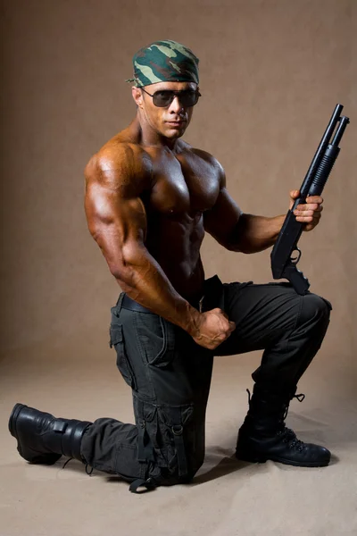 A muscular man with a gun. — Stock Photo, Image