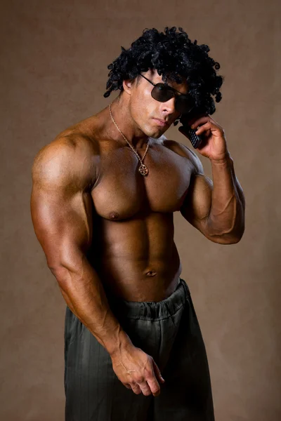 Homem musculoso com cabelo encaracolado falando em um telefone celular . — Fotografia de Stock
