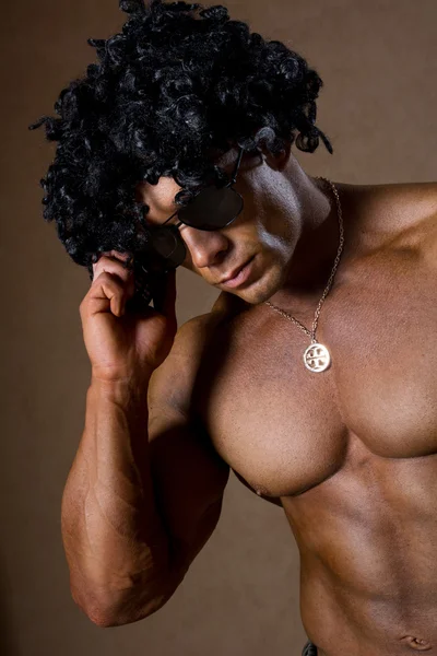Muscular man with curly hair talking on a cell phone. — Stock Photo, Image