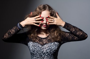 gri bir arka plan üzerinde elleriyle gözlerini kapsayan kadın