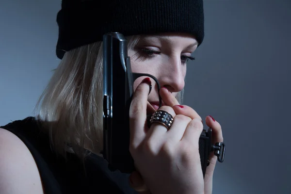 Jeune fille dans une casquette sombre avec un pistolet à la main — Photo