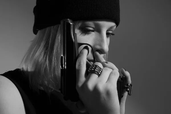 Menina em um boné escuro com uma arma na mão — Fotografia de Stock