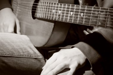 Close-up of guitarist with guitar sits before the performance clipart