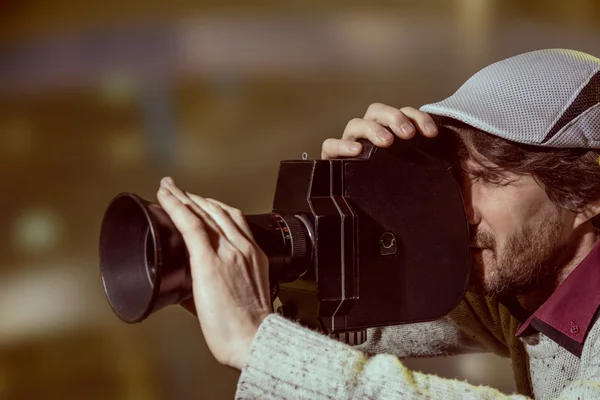 Um homem usando um boné com uma câmera de filme antiga — Fotografia de Stock