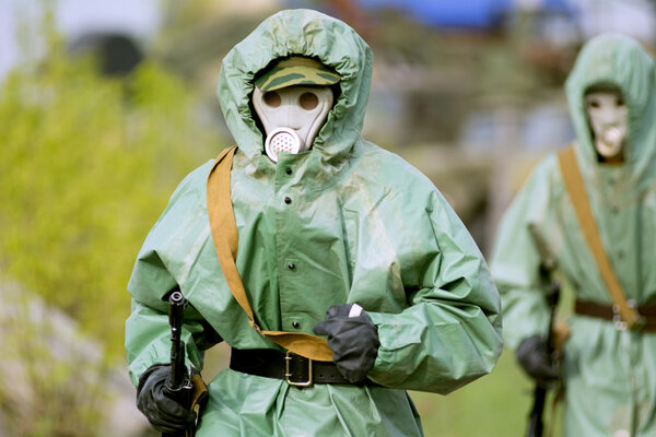 Military man in protective suit and gas mask outdoors. 