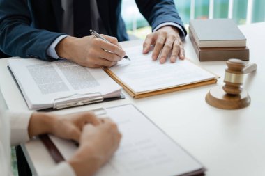 Avukat hukuk danışmanı müvekkiline tokmak ve hukuk hukuku ile imzalanmış bir sözleşme sunar. Adalet ve Avukat İş ortaklığı toplantısı