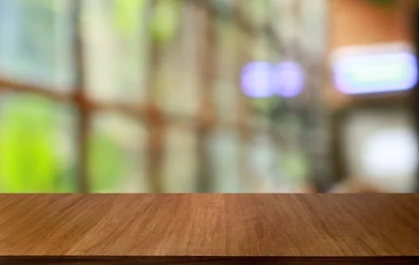 Empty wooden table in front of abstract blurred background of coffee shop . wood table in front can be used for display or montage your products.Mock up for display of produc