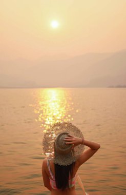 Bikini giyen mutlu Asyalı kadın yaz tropikal plaj tatili mutlu genç kız şık bir kravat boyası bikini ve güneş gözlüğü giyiyor mayo plajı yaz tatilinde bronzlaşmış.