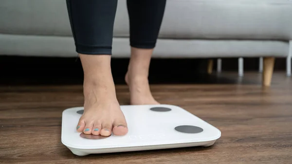 feet standing on electronic scales for weight control. Measurement instrument in kilogram for a diet control.