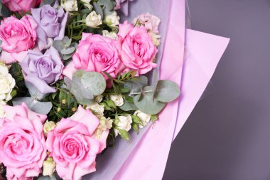 Büyük renkli bir buket çiçek. Büyük pembe güller ve okaliptüs yaprakları. Aydınlık bir arkaplanda, yan görüş. Tatil konsepti