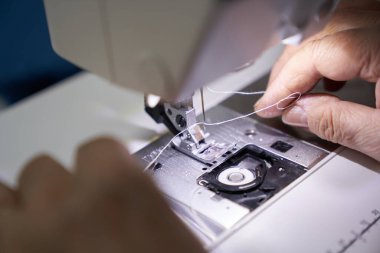 Bir terzinin işyeri. Terzi bir dikiş makinesinde çalışıyor. Bir terzi iş yerindeki dikiş makinesine iplik bağlıyor. Hobi dikiş işi küçük bir iş konseptidir.