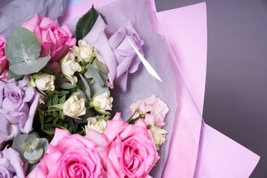 Büyük renkli bir buket çiçek. Büyük pembe güller ve okaliptüs yaprakları. Aydınlık bir arkaplanda, yan görüş. Tatil konsepti