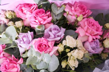 Büyük renkli bir buket çiçek. Büyük pembe güller ve okaliptüs yaprakları. Aydınlık bir arkaplanda, yan görüş. Tatil konsepti