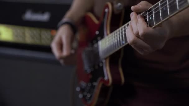 Primer plano de un hombre esperando para tocar una guitarra electrónica. En el fondo, un amplificador de sonido, un sistema de audio. Equipo de concierto de sonido. — Vídeos de Stock