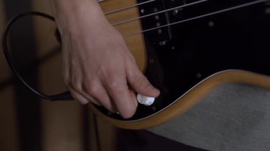 Elektronik gitarı akort eden bir adamın yakın çekimi. Ses konser ekipmanı.