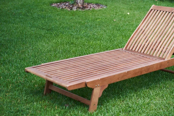 Tahta şezlong yeşil çimlerin üzerindeki taze bahçede.