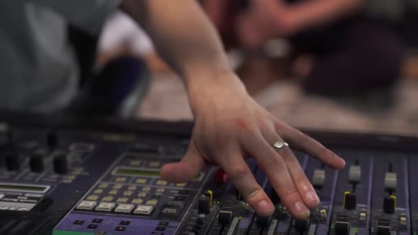 Close-up dari tangan laki-laki mengendalikan suara, sebuah konsol pencampuran profesional di studio, dengan lampu latar LED — Stok Video