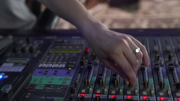 Närbild. Professionell mixningskonsol i studion, en mans hand styr ljudet, med LED-bakgrundsbelysning — Stockvideo