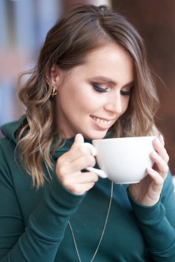 İyimser, güzel bir esmer kadının elinde fincanla bir kafede otururken bir kızın fincana baktığı fotoğraf.