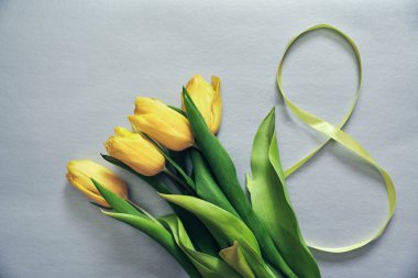 Gri arkaplanda beş sarı lale ve sekiz numaralı kurdele.