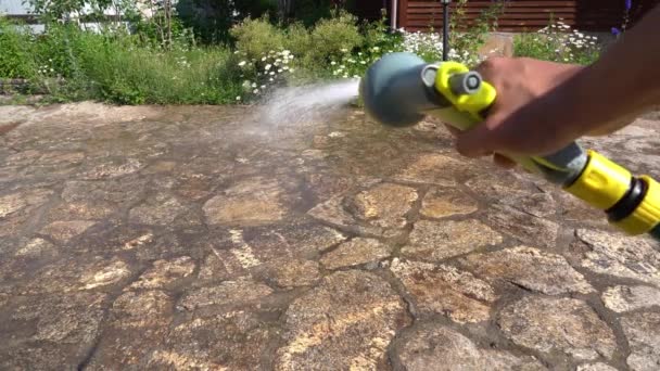 De oprit onder druk wassen, een mensenhand onder druk spuit een waterige oplossing op de stoep in de buurt van het huis als onderdeel van zijn dienst. — Stockvideo