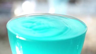 Dalgalı bir damla su. Yavaş çekimde, bir damla su bir bardak turkuaz sıvıya düştü ve yüzeye sıçradı..