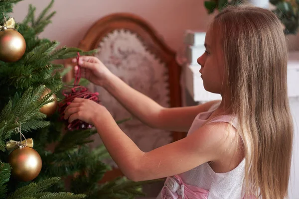 Küçük bir kız Noel ağacını süslerle süslüyor. Yeni yıl için hazırlık.