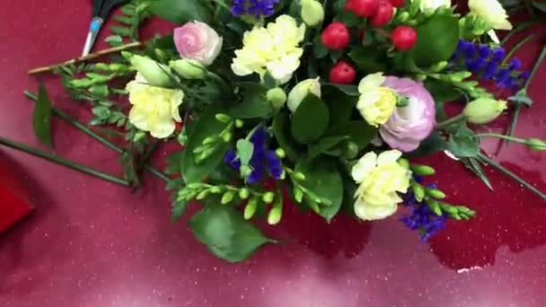 Oficina floral, fazendo buquês de flores diferentes. Uma mulher recolhe um buquê de flores. Pessoas em processo de trabalho. — Vídeo de Stock