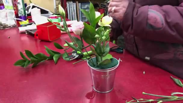 महिला लोहे की बाल्टी में फूलों का गुलदस्ता इकट्ठा करना शुरू कर देती है। विभिन्न फूलों, फूल कार्यशाला के गुलदस्ते बनाना। काम की प्रक्रिया में लोग . — स्टॉक वीडियो