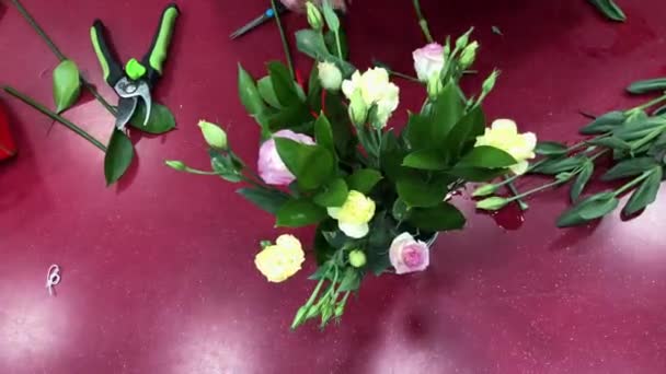 Kobieta kwiaciarnia zaczyna zbierać kompozycję różnych kwiatów. Produkcja bukietów, kwiaciarnia. Ludzie w trakcie pracy. — Wideo stockowe