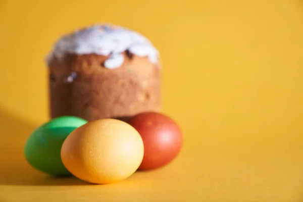 Farbige Ostereier auf dem Hintergrund einer Ostertorte. Gelber Hintergrund mit Leerzeichen zum Kopieren — Stockfoto