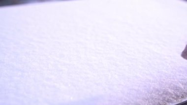 Soğuk bir kış gününde beyaz kar, yakın plan. Bir adam parmaklarıyla kara kalp çizer. Doğal arkaplan.