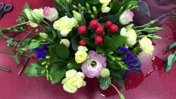 Die Frau sammelte einen Blumenstrauß ein. Blumenwerkstatt, Herstellung von Sträußen in verschiedenen Farben. Menschen im Arbeitsprozess. — Stockvideo