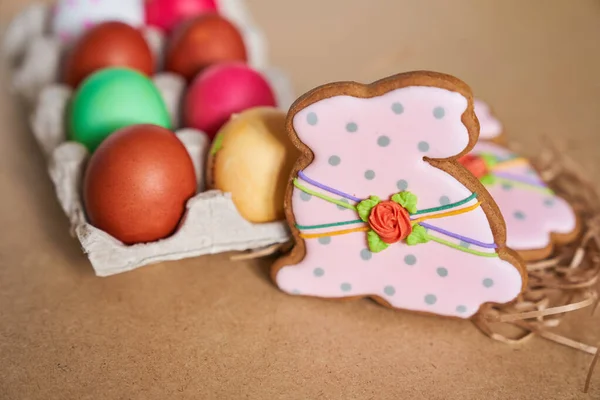 Ostereier und Lebkuchen in Hasenform auf sandigem Untergrund. Minimales Konzept. Mit Raum zum Kopieren — Stockfoto