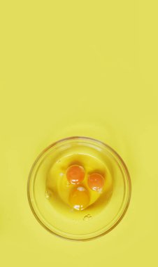 Sağlıklı yiyecekler. Sarı arka planda üç çiğ yumurta ve kopyalayacak bir yer. Kahvaltı hazırlama konsepti