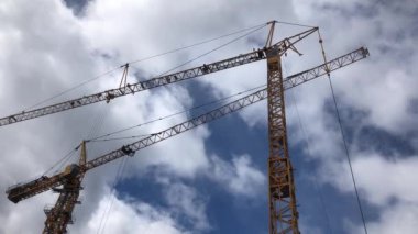 Mavi gökyüzünde iki sarı vinç, güzel bulutlar, inşaat işleri.