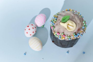 Beyaz Paskalya yumurtaları kalp ve çizgi şeklinde bir desen ve çiçek desenli bir pasta. Gölgeli mavi arkaplan görünümlü Ortodoks Paskalyası.