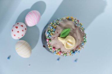 Beyaz Paskalya yumurtaları kalp ve çizgi şeklinde bir desen ve çiçek desenli bir pasta. Gölgeli mavi arkaplan görünümlü Ortodoks Paskalyası.