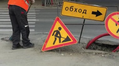 Bir belediye işçisi bir süpürgeyle yolu süpürüyor. Yol işaretleri. Yol tamiri. Yol tabelası, yol tamiri, sağdaki engelleri aşmak..