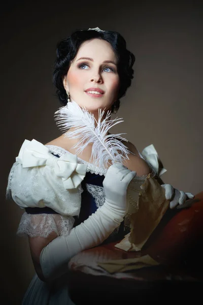 Una dama con una sonrisa en un traje histórico con una pluma en la mano y una carta. Diseño para la portada del libro. Fotos De Stock Sin Royalties Gratis