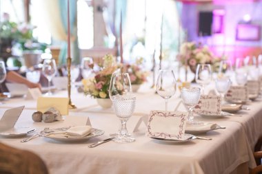 Pastel renkte bir tatil için lüks bir masa. Restorana yerleştirilmiş boş şarap bardakları. İç kısmın bir kısmı