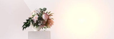 Banner, beyaz bir vazoda farklı renkte bir kompozisyondur. Görüntünün merkezinde, güneş ışığı bir pıhtıdır. Taze kesilmiş güzel bir buket.