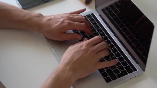 Κάτοψη close-up των αρσενικών χεριών πληκτρολογώντας στο πληκτρολόγιο σε αναζήτηση πληροφοριών. Η έννοια της εξ αποστάσεως εργασίας. — Αρχείο Βίντεο