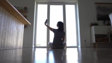 Mutlu bir kadın elini sallıyor ve akıllı telefon uygulaması kullanıyor. Uzaktan arkadaşlarla sanal bir online sohbetin tadını çıkarmak, mobil bir sohbetin içinde sanal bir görüşme..