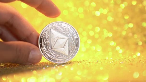 Žena ukazuje jedno stříbrné éterium na zlatě lesklém pozadí. Investice do ethereum cryptocurrency business. — Stock video