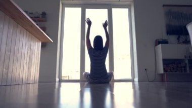 Pencerenin arkasındaki bir kadın yoga derslerini bitiriyor. Tanımlanamayan hamile bir kadın lotus pozisyonunda yoga yapıyor. Sırtı kameraya dönük.