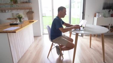 Yazan genç adam serbest çalışan biri. Modern bir dizüstü bilgisayarla evde otururken uzaktan çalışıyor..