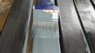 Bir ressam paslanmayı önlemek için çeliğe astar boyuyor..